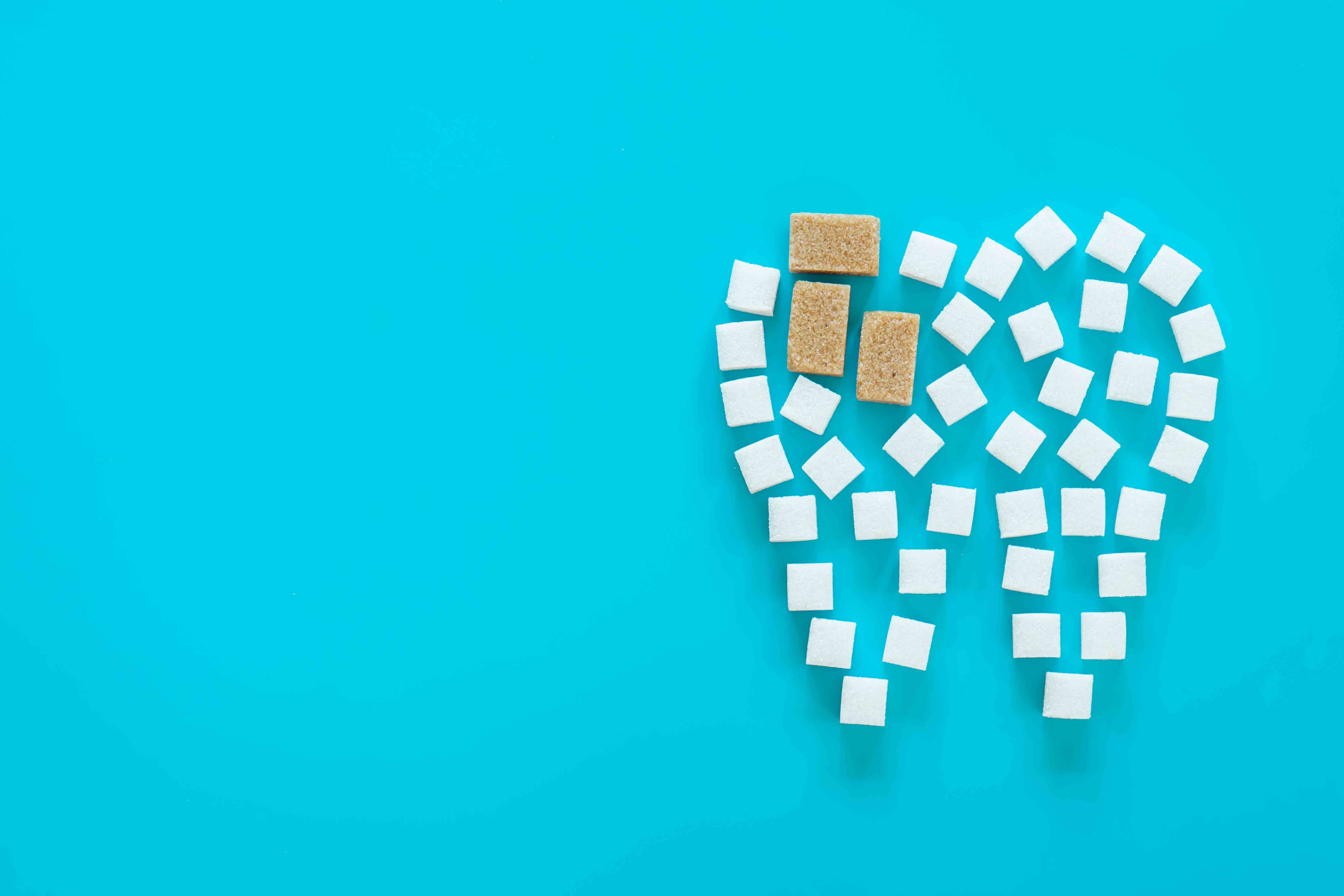 Tooth shape made from white and brown sugar cubes on a blue background.