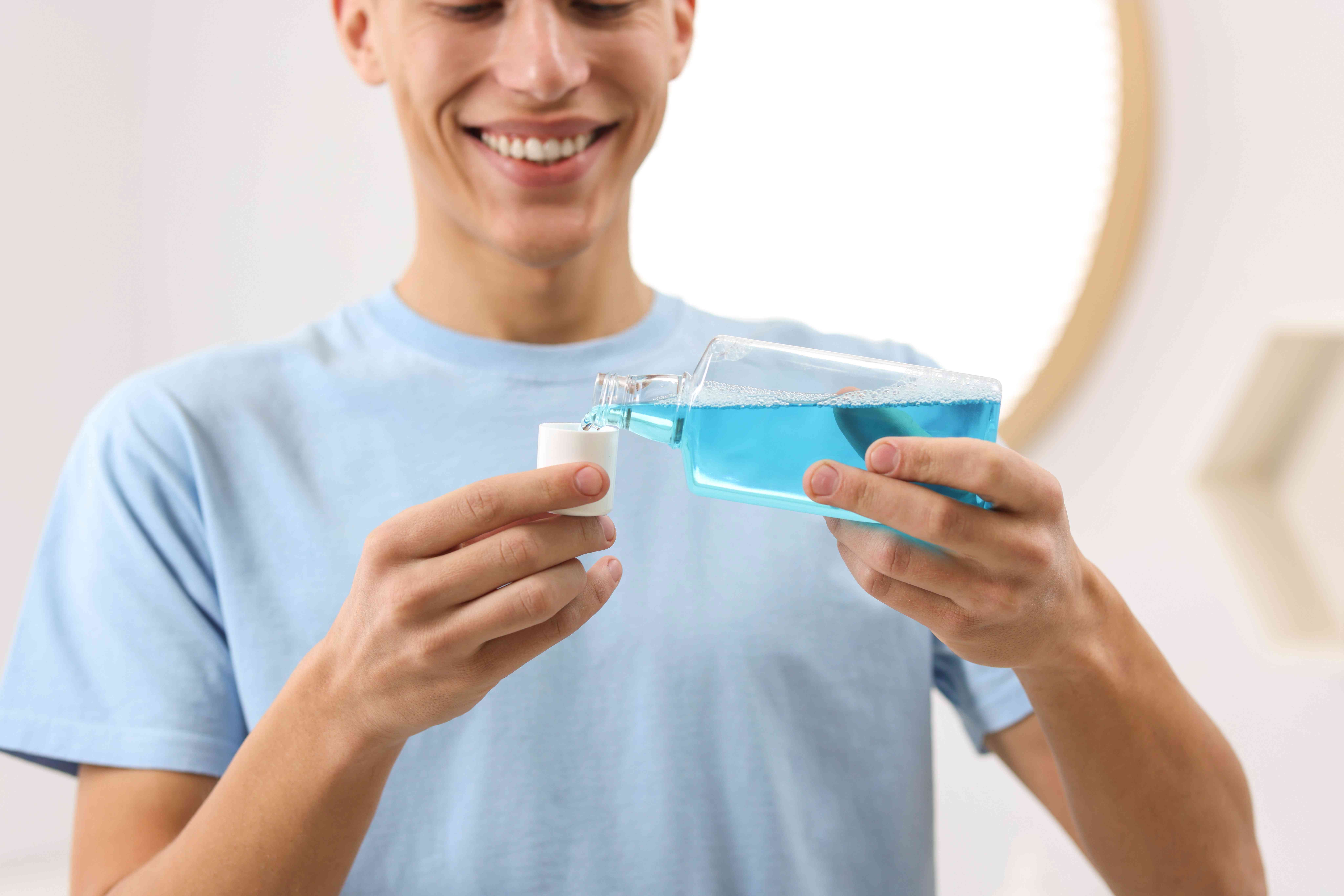 young-man-using-mouthwash-bathroom-closeup (1)-compressed