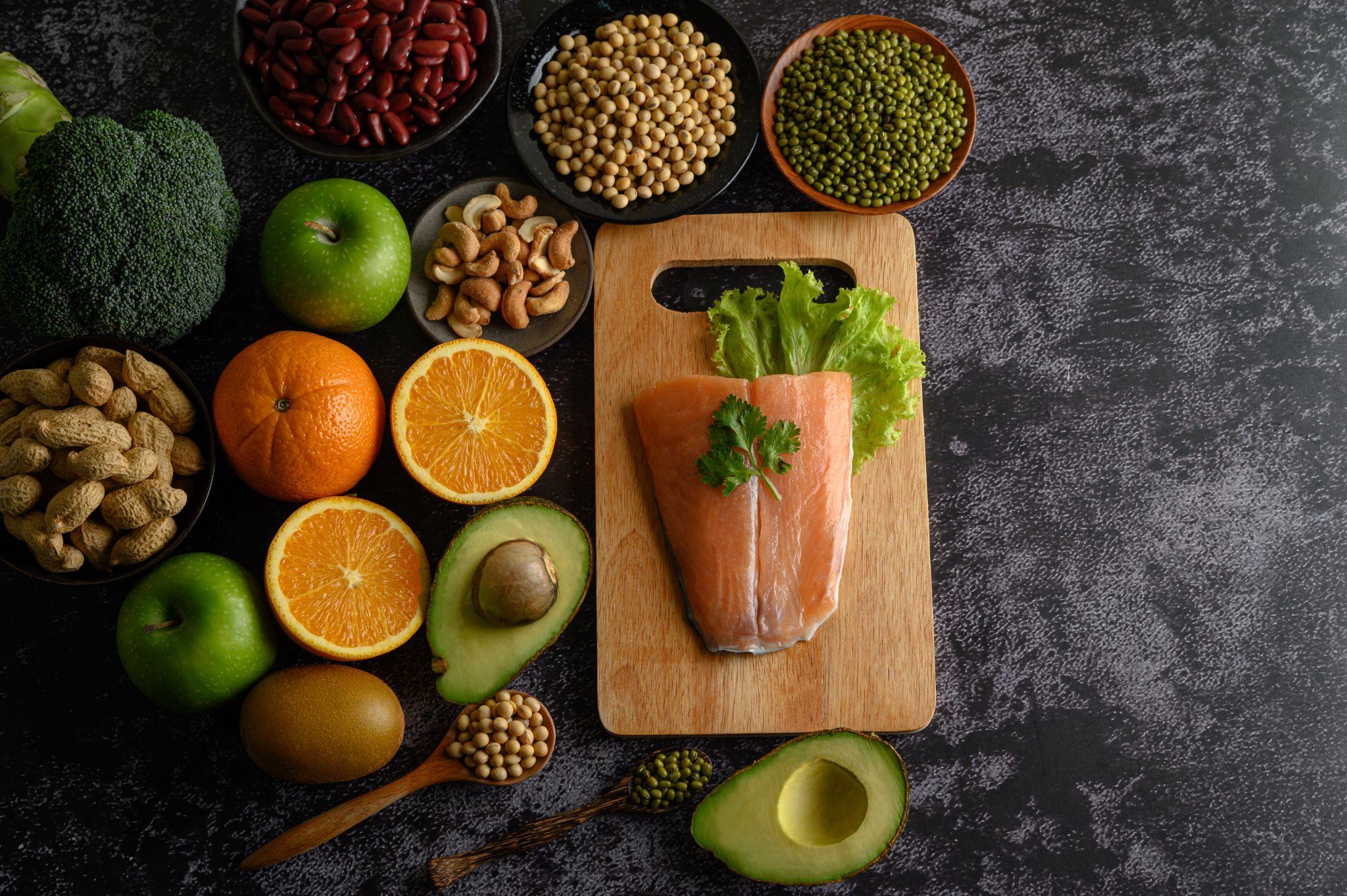 Legumes, fruits, salmon fish pieces on the chopping board and table.