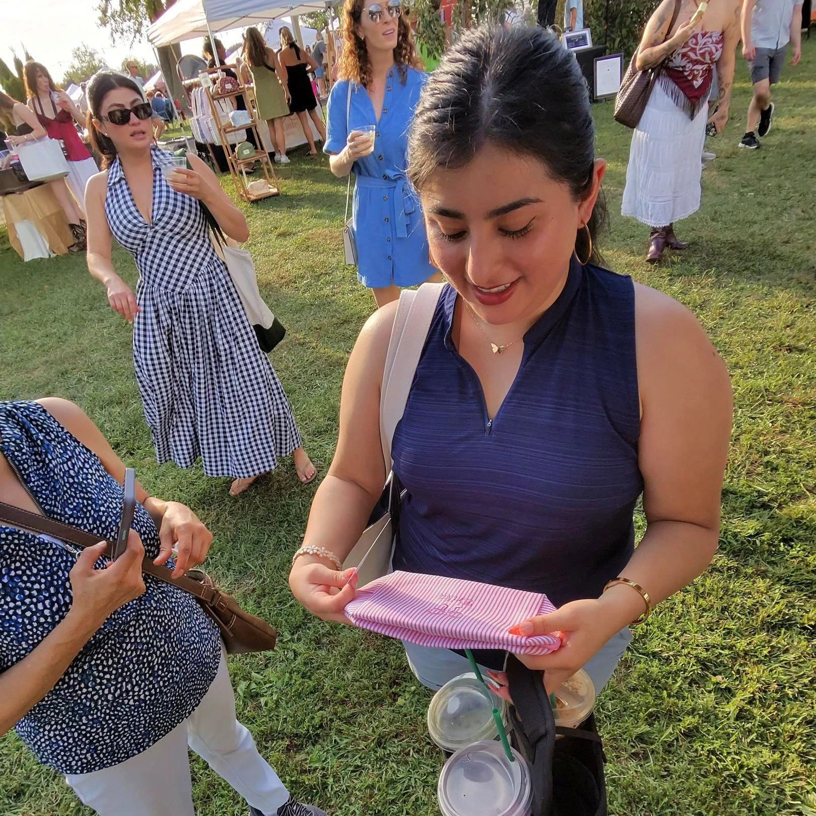 Woman looking at her custom embroidered bag from live embroidery at Solara Market in Noblesville, IN