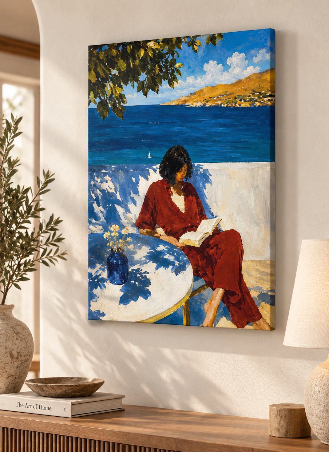 Woman in a red outfit reading a book beside deep blue sea, with golden hills, leafy branches, and a vase of flowers in a painterly coastal scene.
