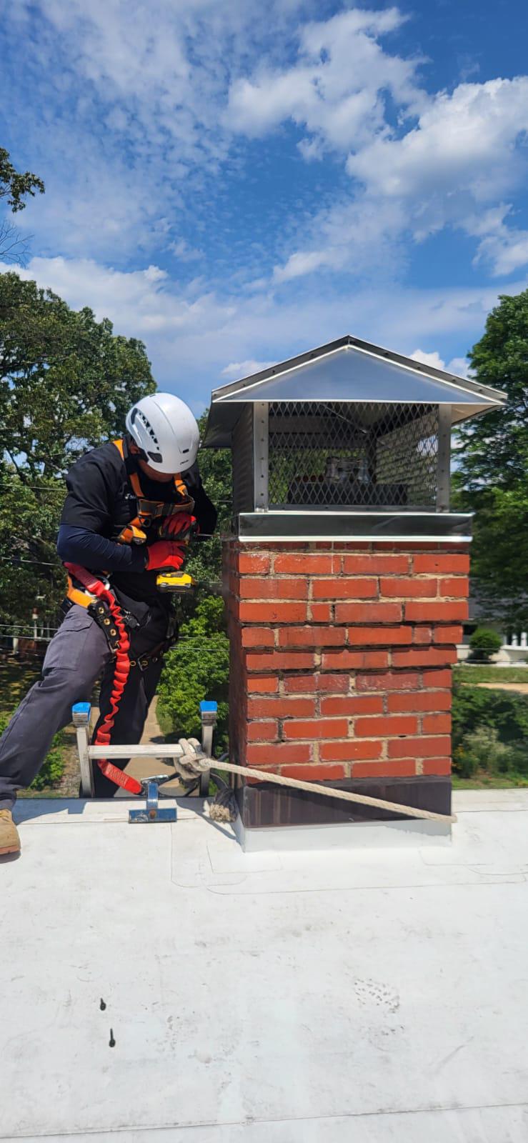 Worker installing mount cap on brick chimney using power drill