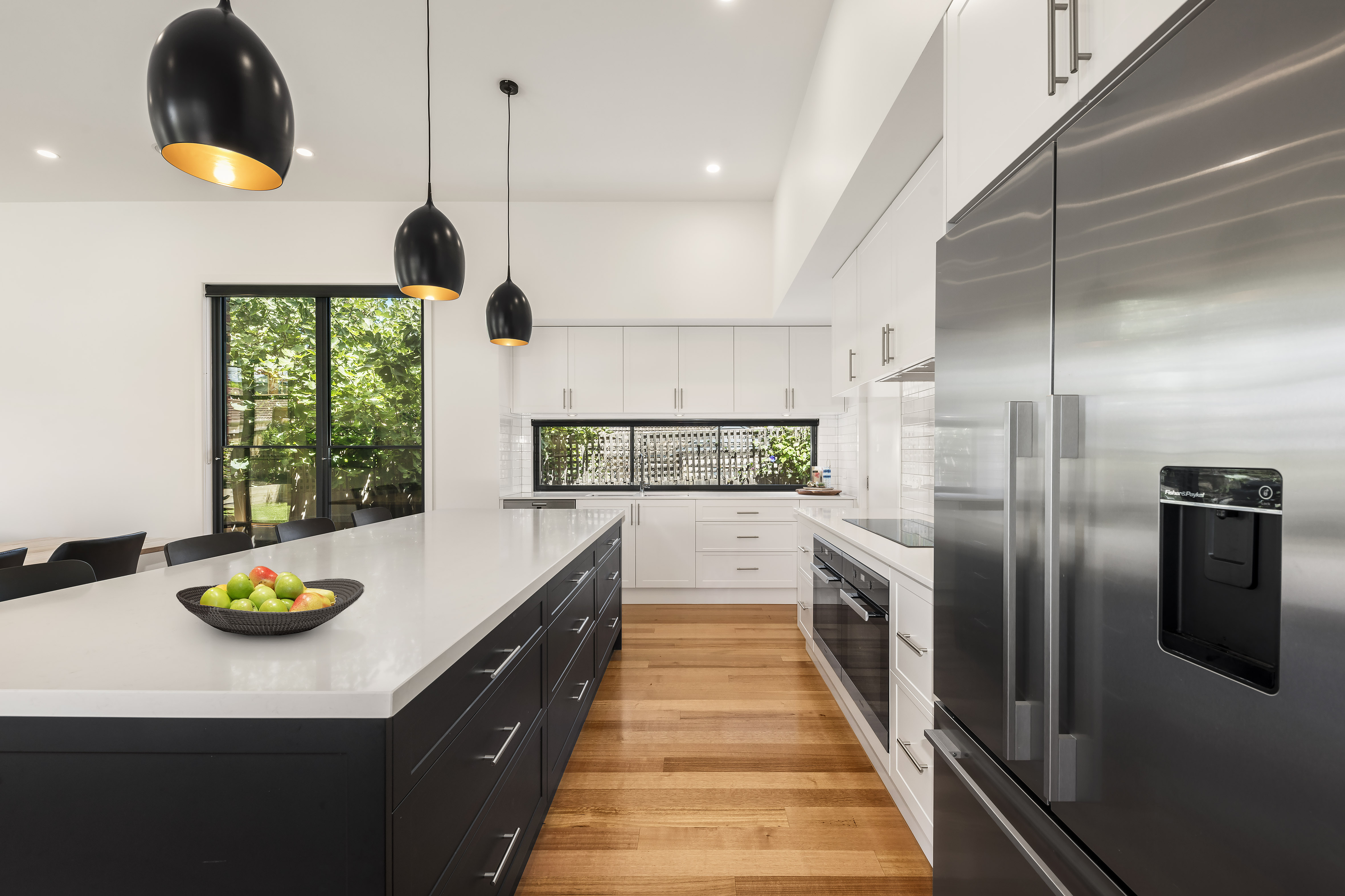 Modern kitchen with large island featuring white countertop and dark cabinetry