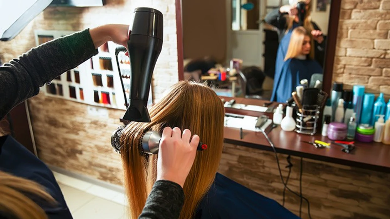 Stylist using a hairdryer on a client's hair at a beauty salon