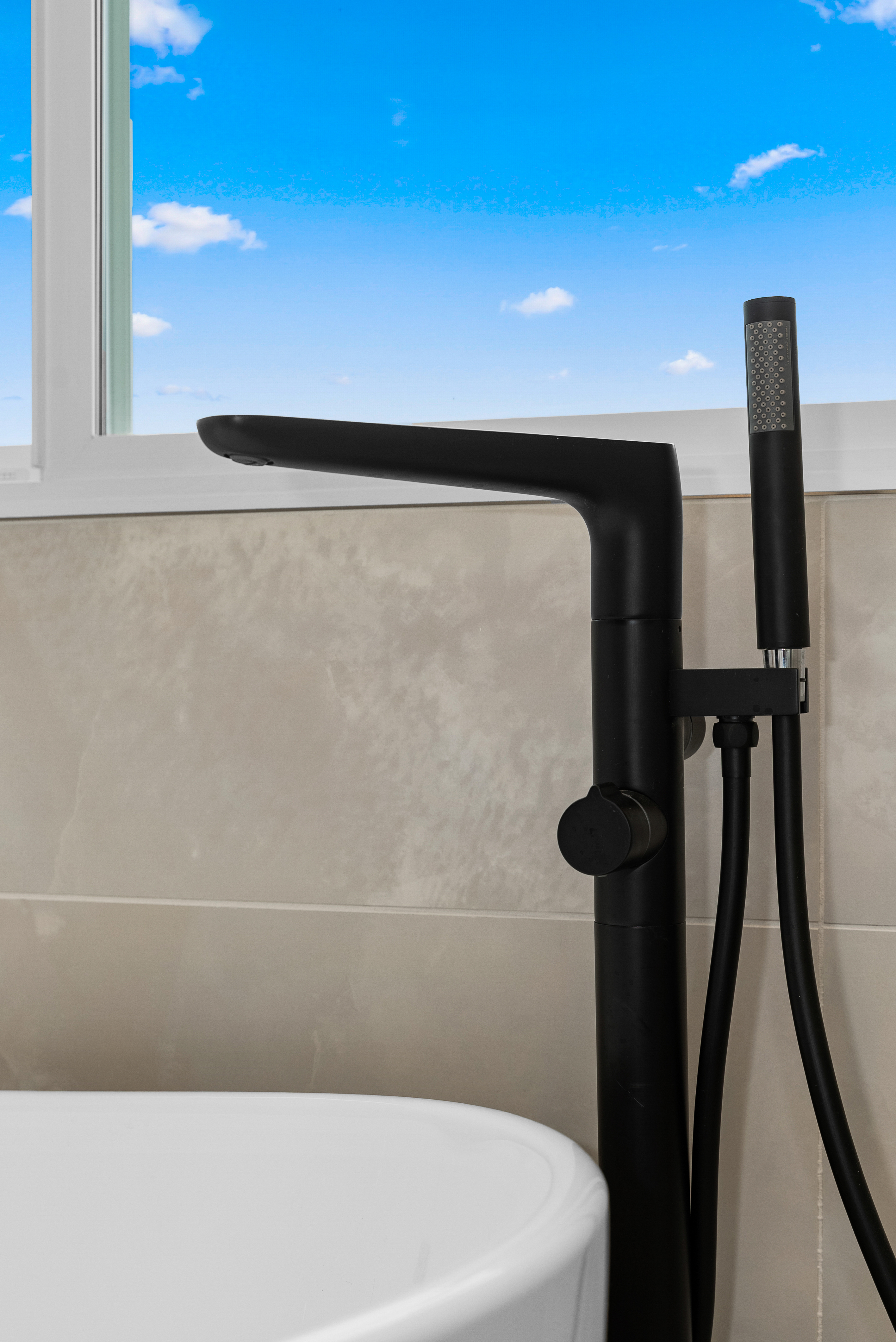 Matte black freestanding bathtub faucet with hand-held shower head