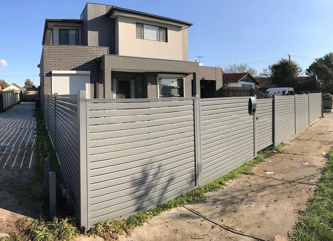 Steel slat security fence surrounding a modern two-story house