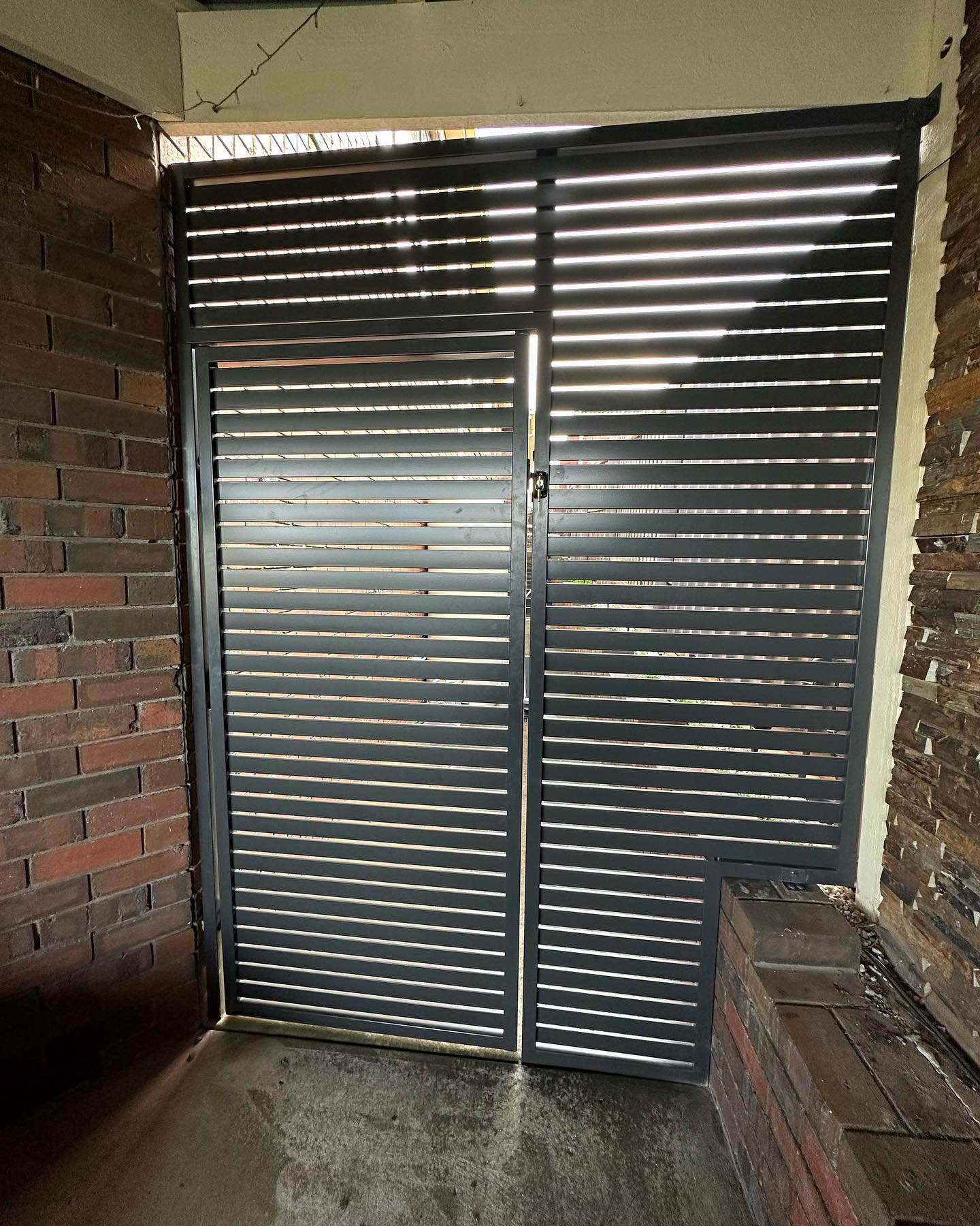 Custom slat gate with horizontal slats painted dark