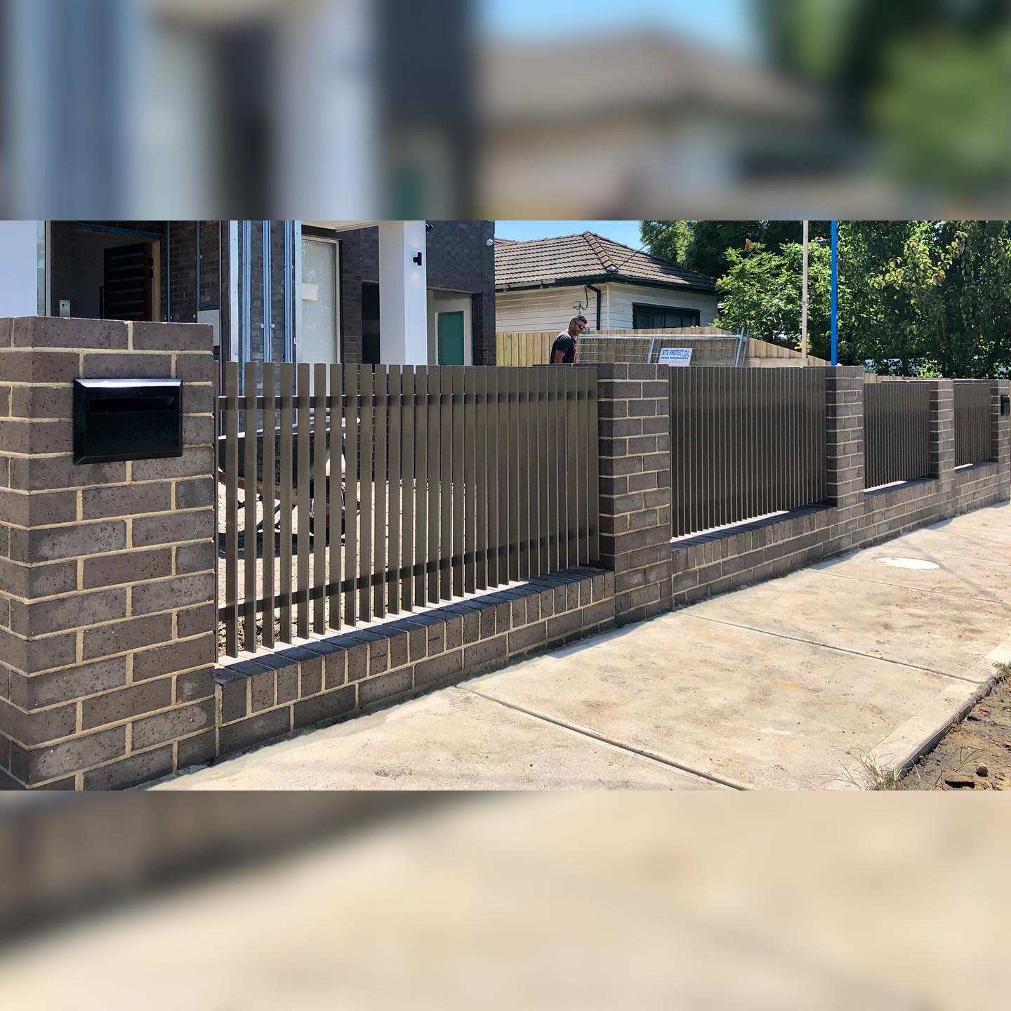 Modern Jasper Powder-Coated Blade Fence Enhances Twin Townhouse Development in Strathmore 2 Modern blade fence with Jasper powder-coated finish integrated into brick wall structure