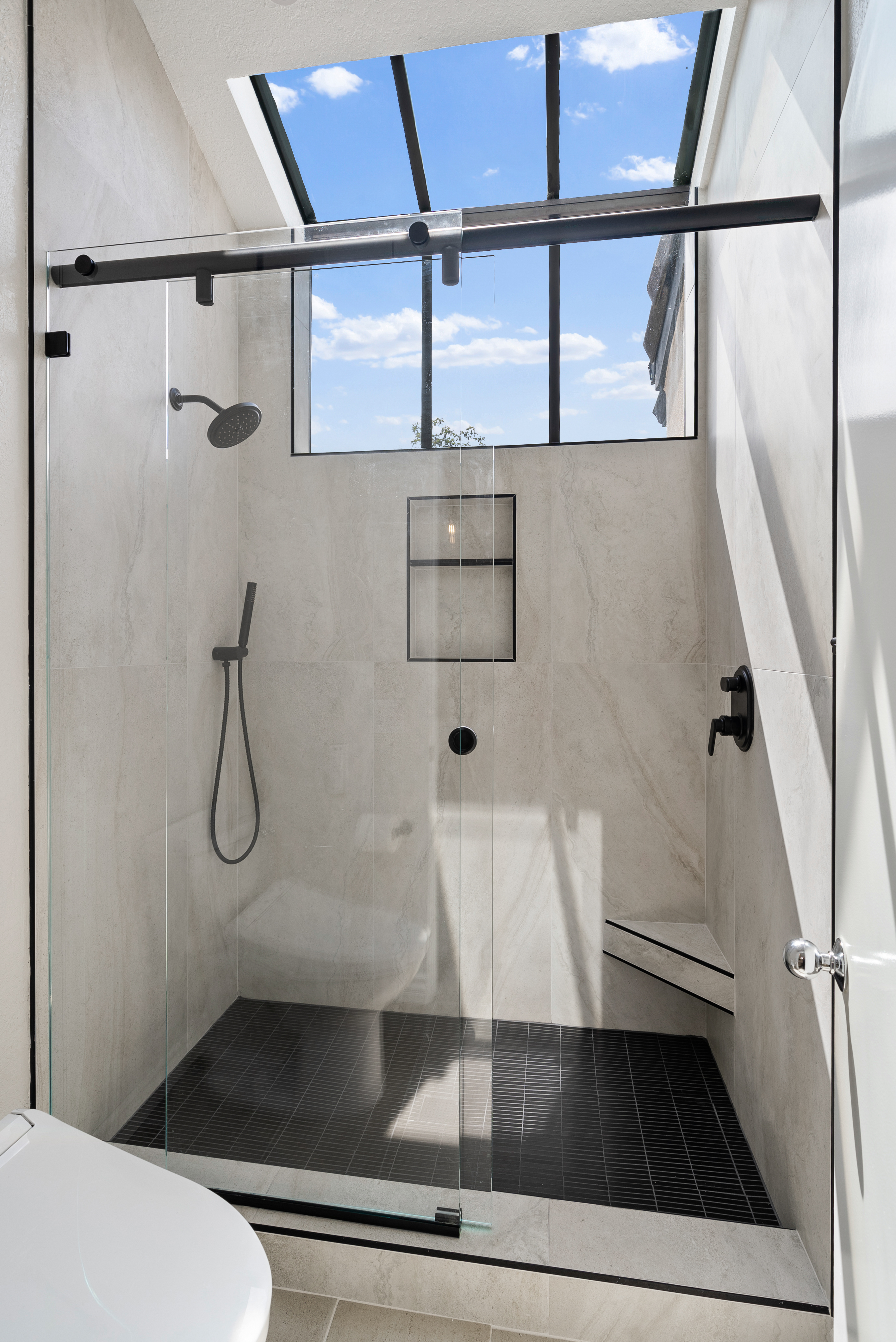 Sleek curved glass shower enclosure with natural light from above