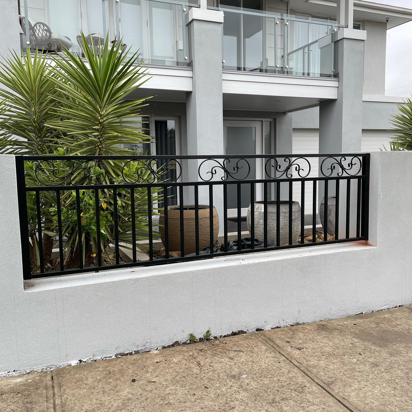 Decorative black metal fence with concrete base