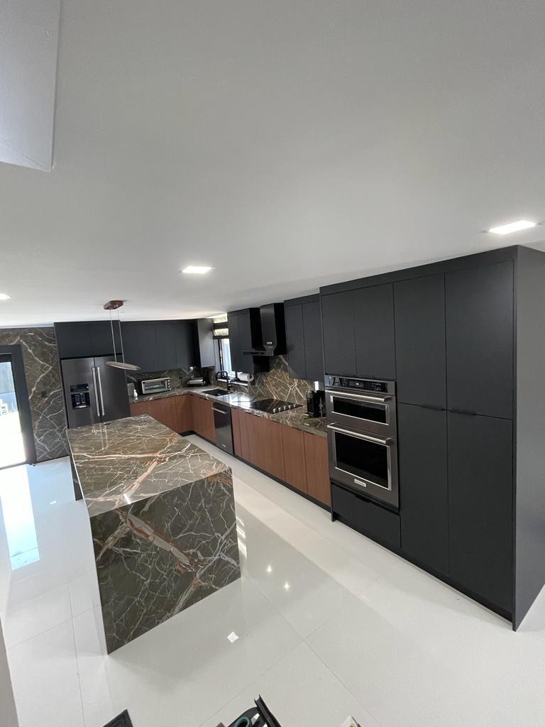 Modern kitchen featuring dark cabinetry and marble island