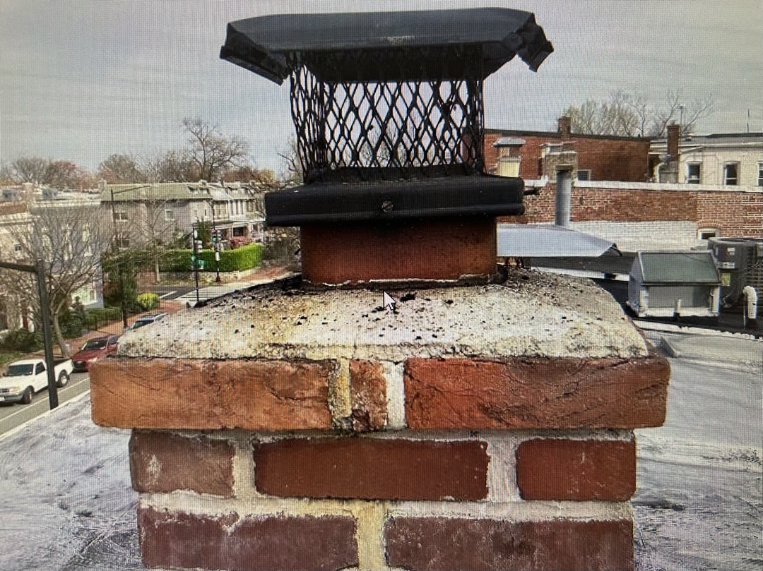 Chimney cap and crown wear visible on top of brick structure