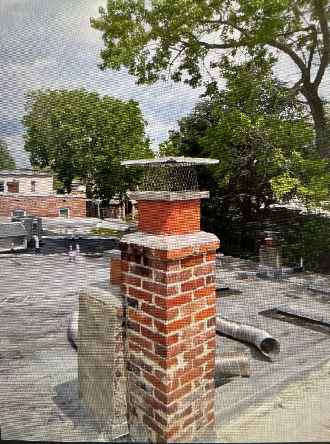 Red brick chimney with new metal cap installed