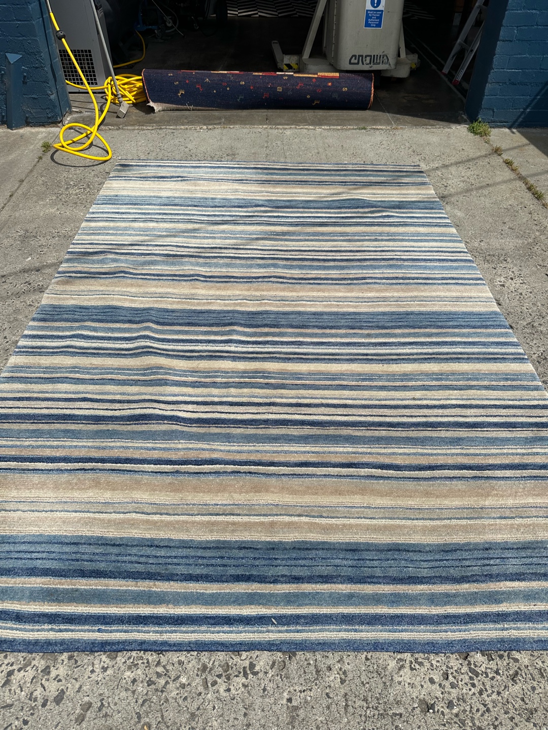 Client observing large striped rug in workshop
