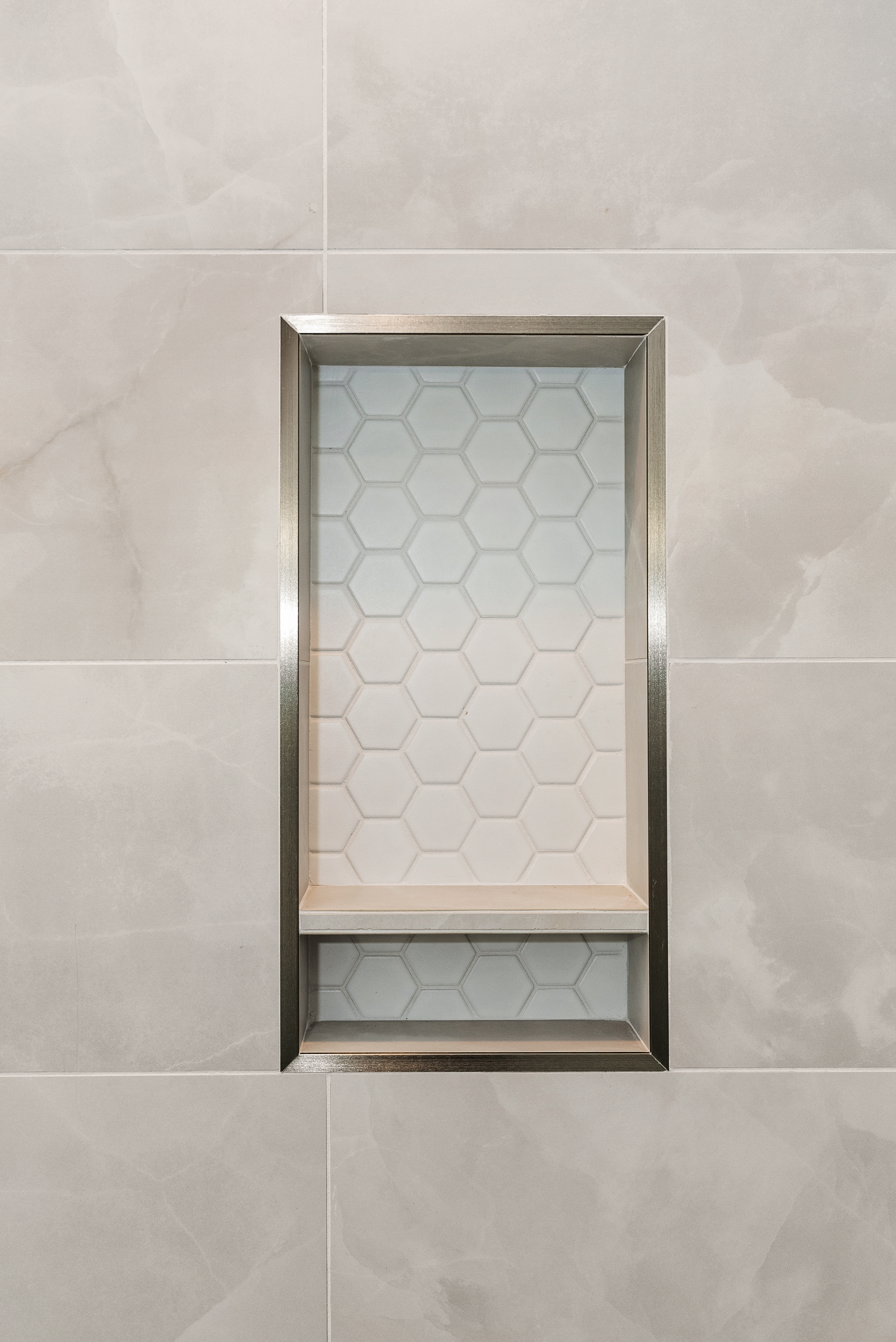 Custom-built niche with brushed metal edge and porcelain tiles