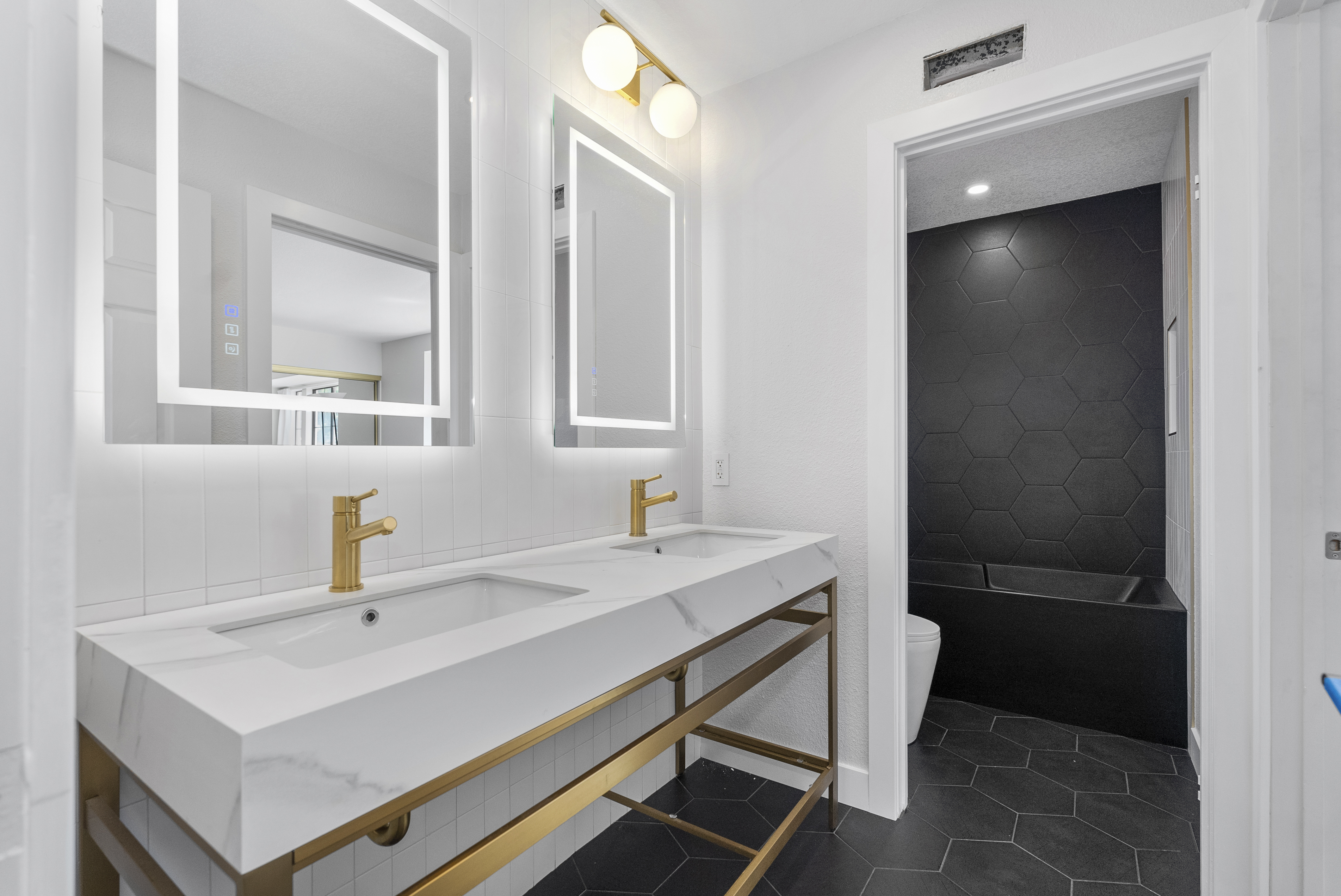 Modern bathroom featuring illuminated mirrors and double vanity