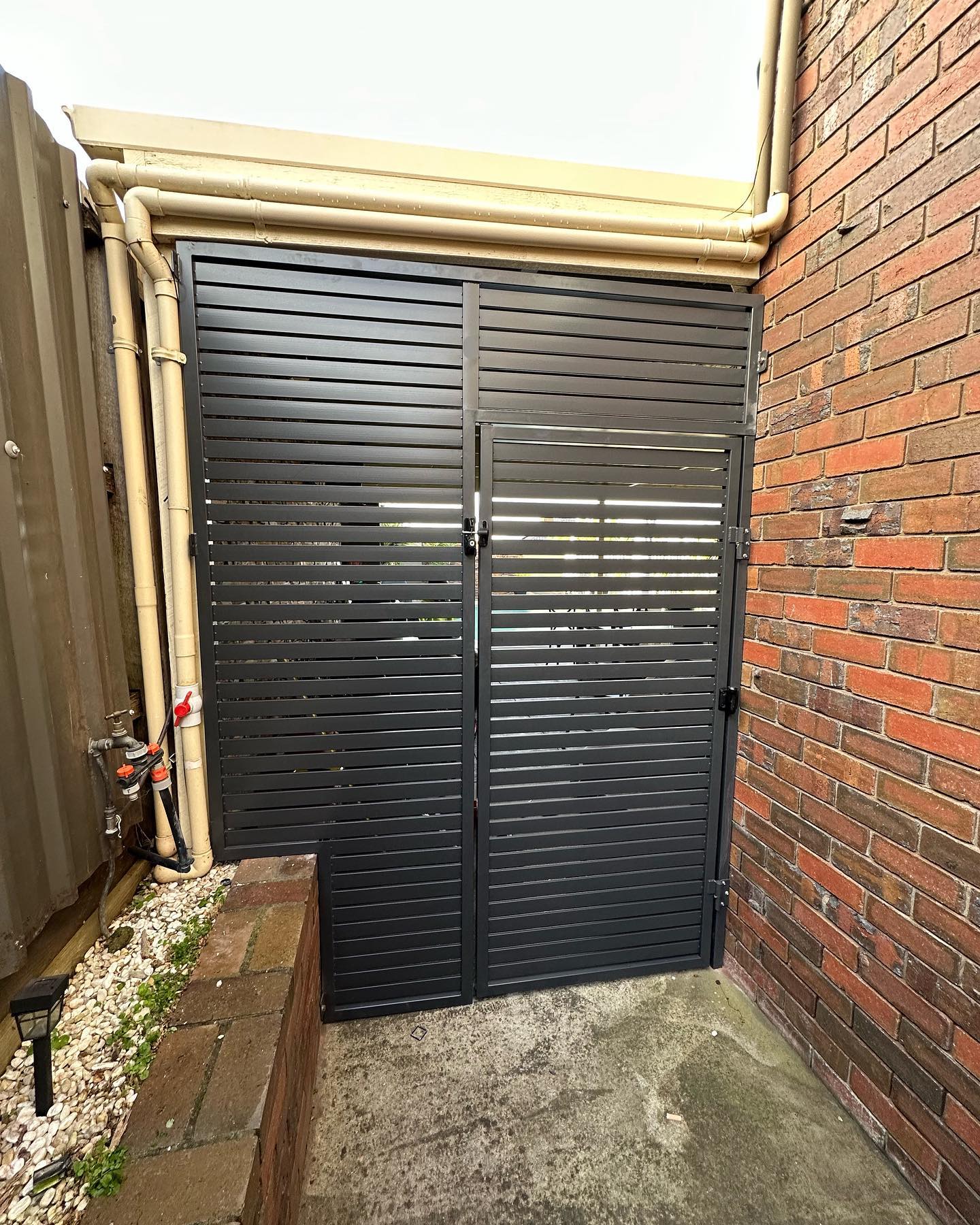 Black metal slatted gate with integrated door