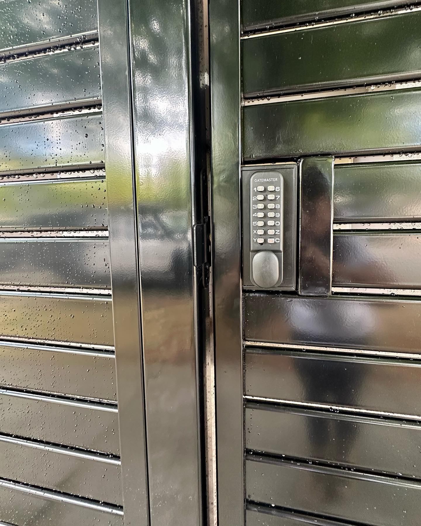 Close-up of custom slat fence gate with water droplets
