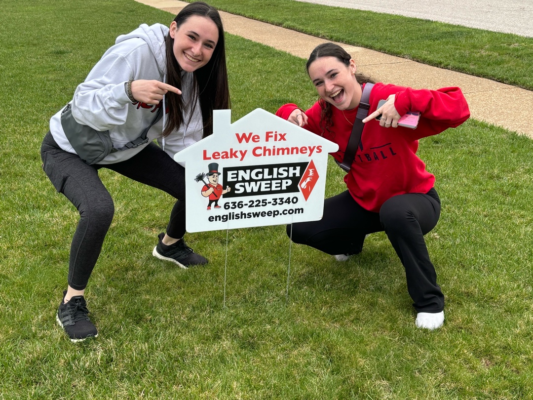Technicians pointing at yard sign promoting English Sweep's services