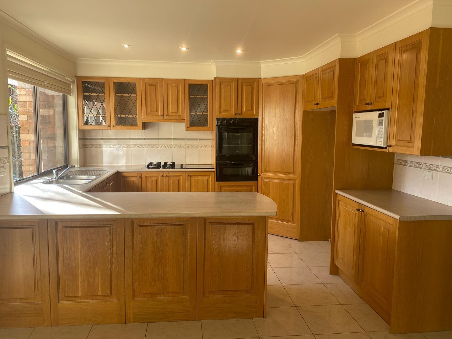 Resurfaced wooden kitchen cabinets with glass-paneled doors
