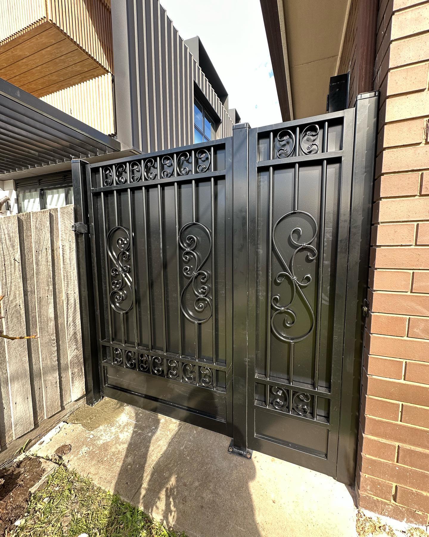 Custom Steel Gate Installation in Rosanna VIC - A Success Story 4 Black steel gate positioned between wooden fence and brick wall