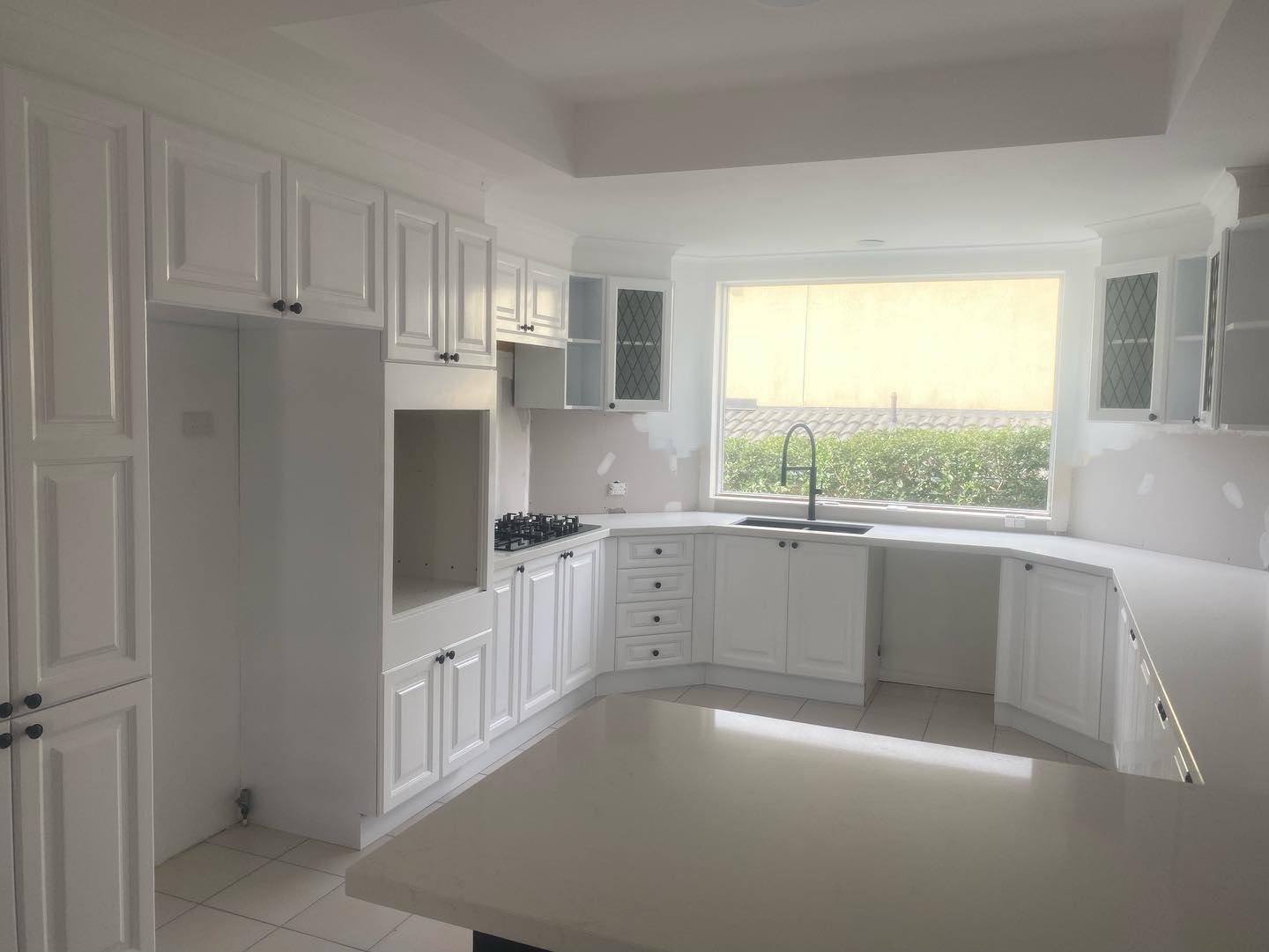 White kitchen cabinets with glossy finish arranged in L-shape