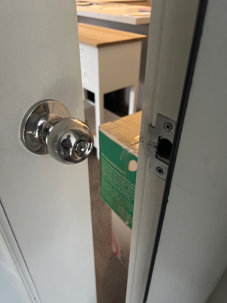 Partially open white door with silver door knob