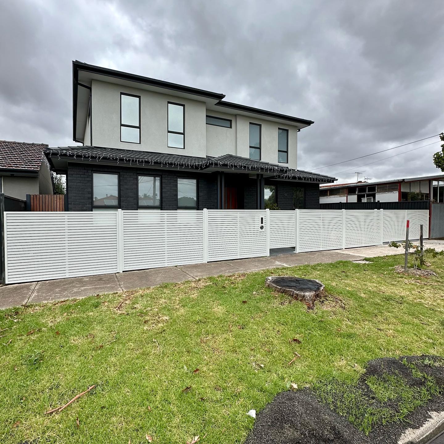 Modern two-story house with white steel slat fence