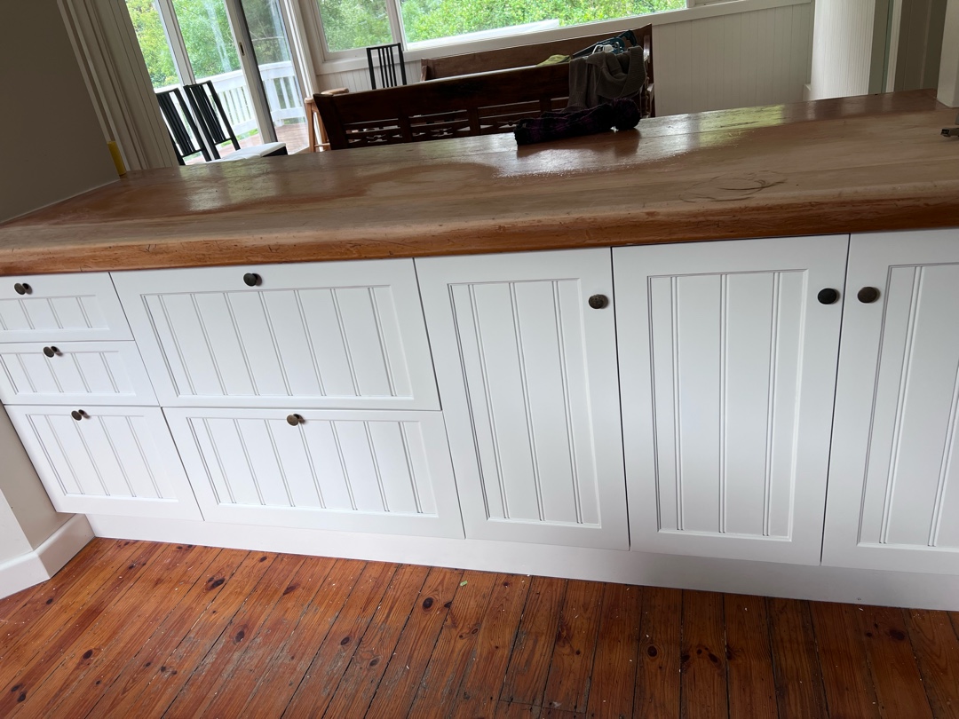 White kitchen cabinets with vertical paneling design and round metal knobs