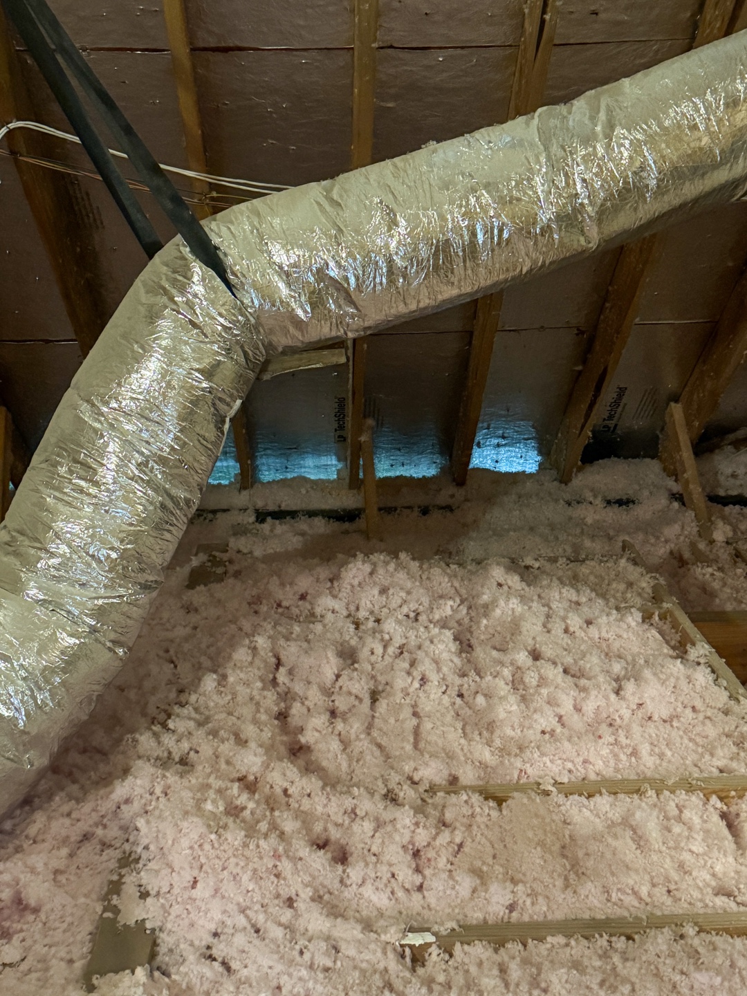 Attic space with visible insulation material spread across the floor