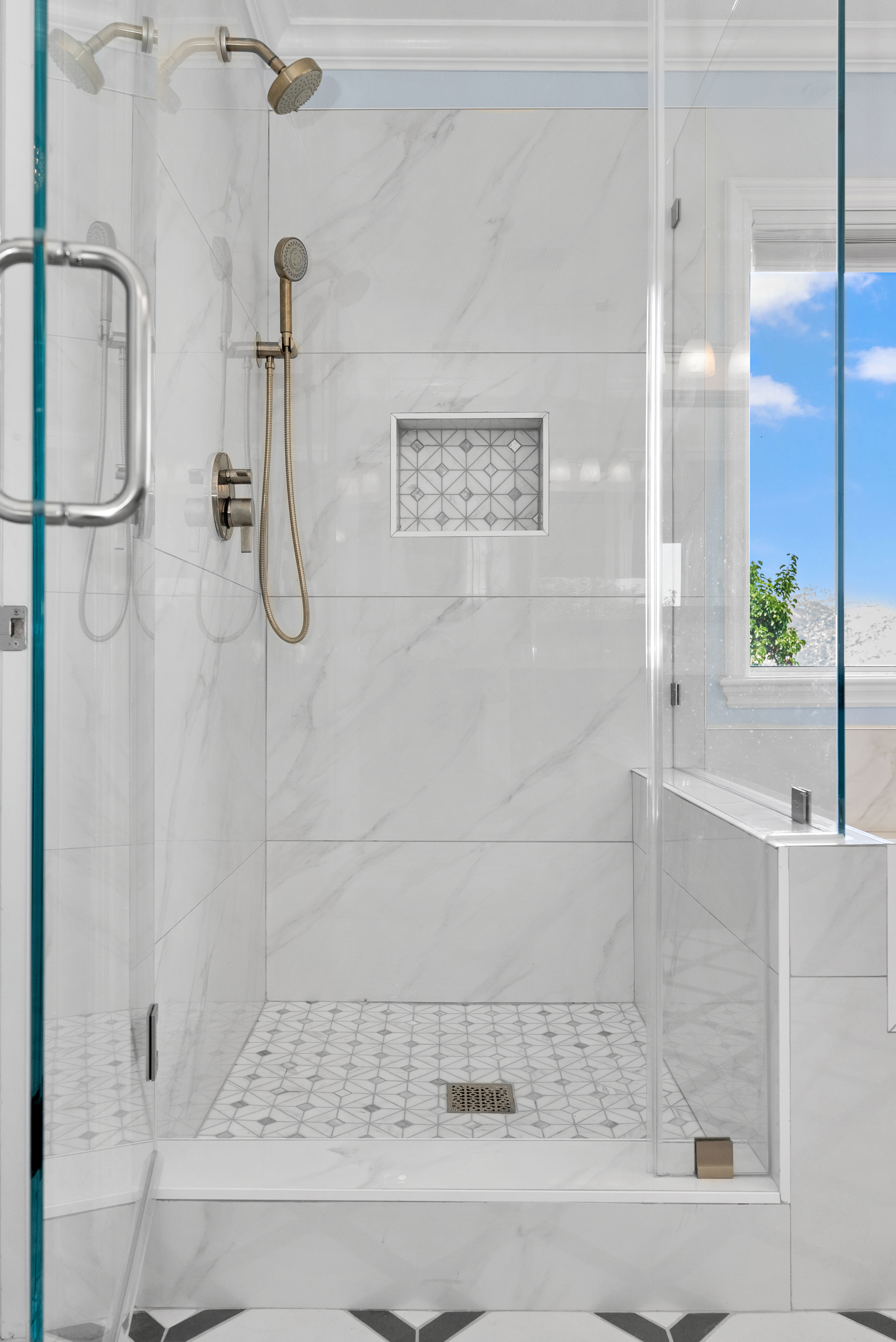 Modern shower area with glass door and marble tiles