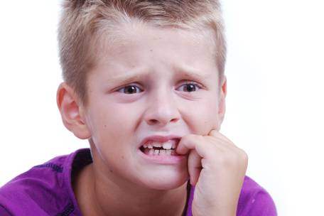 A concerned young boy biting his fingernails, indicating anxiety about transitioning schools