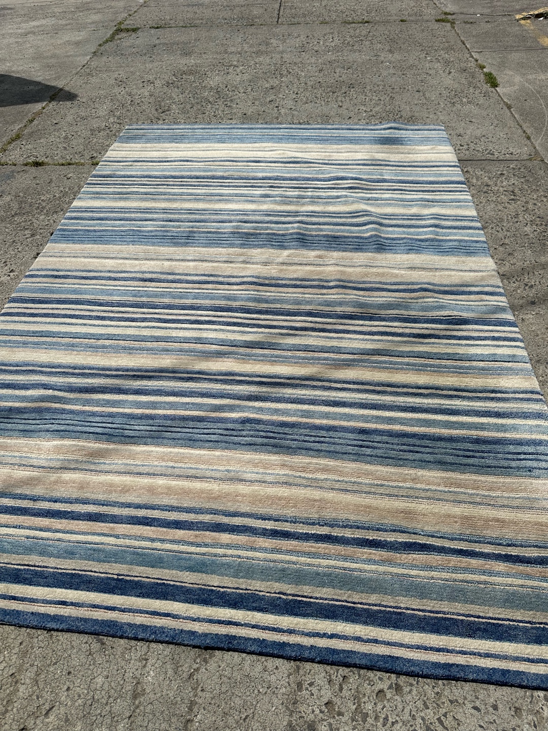 Rug with horizontal blue and beige stripes on concrete surface