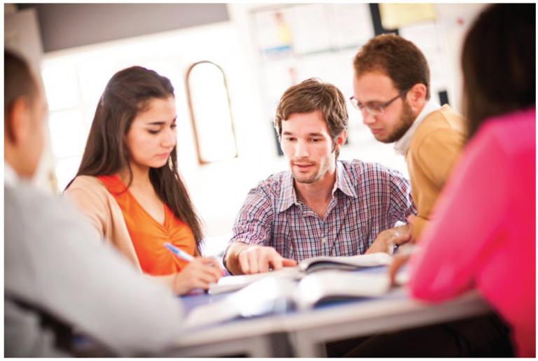 A group of five colleagues discussing around a table, indicative of collaborative peer observation sessions.