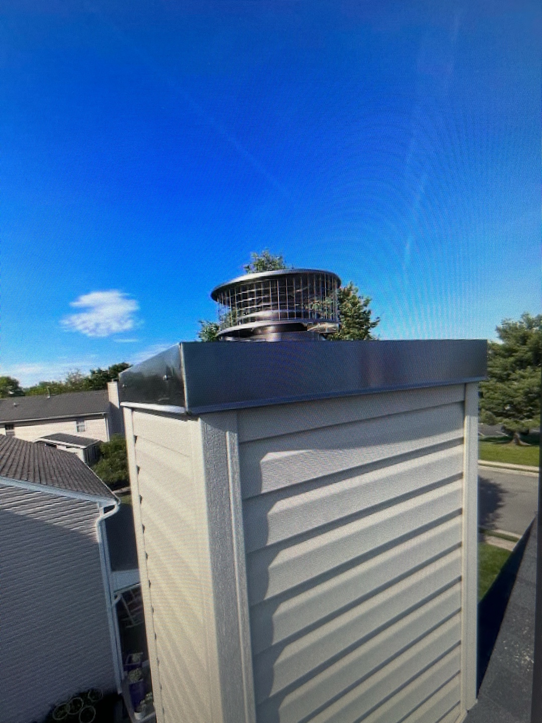 Chimney cap with animal-proof screen installed on a residential building
