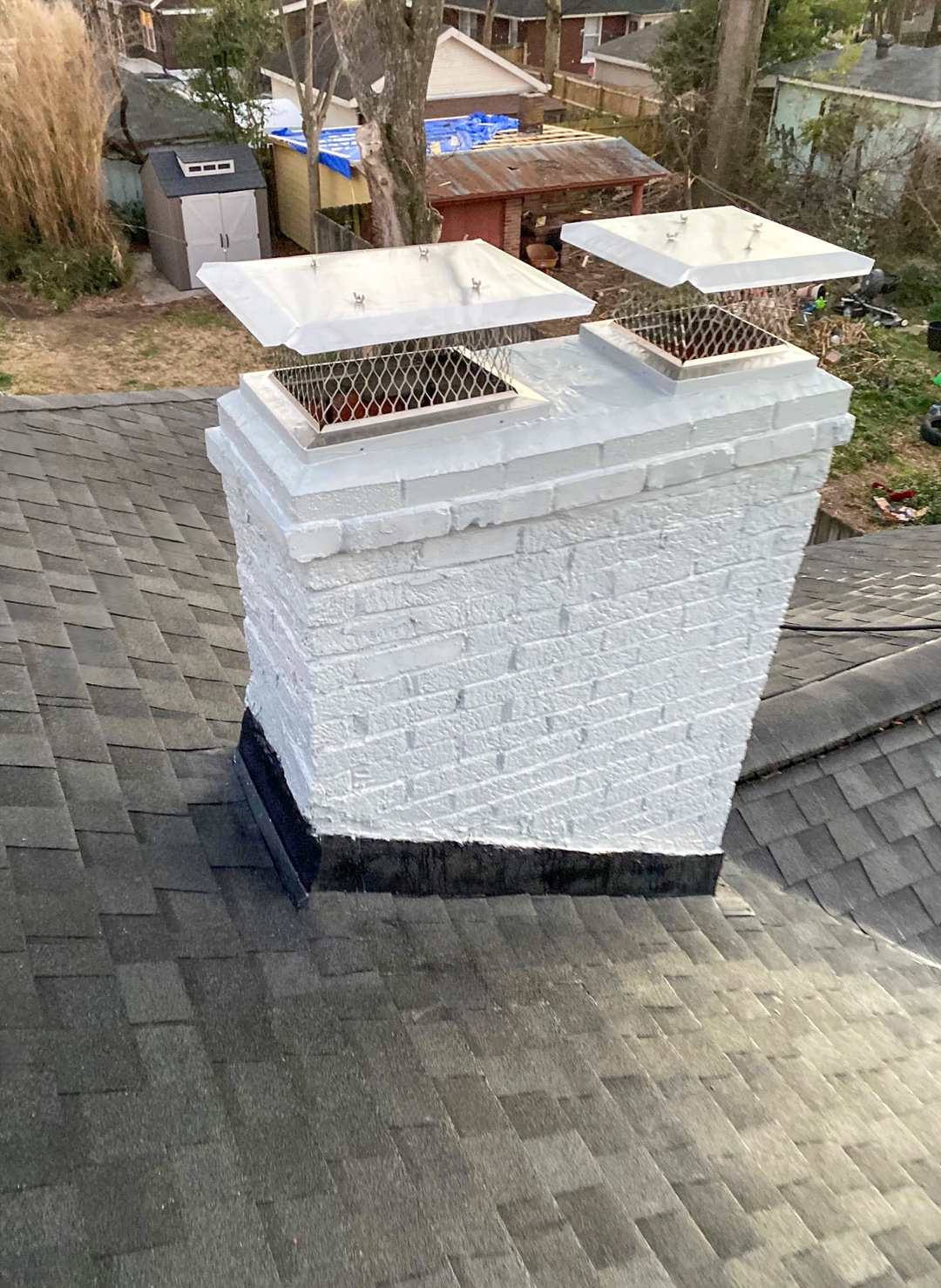 White-painted brick chimney with two metal caps