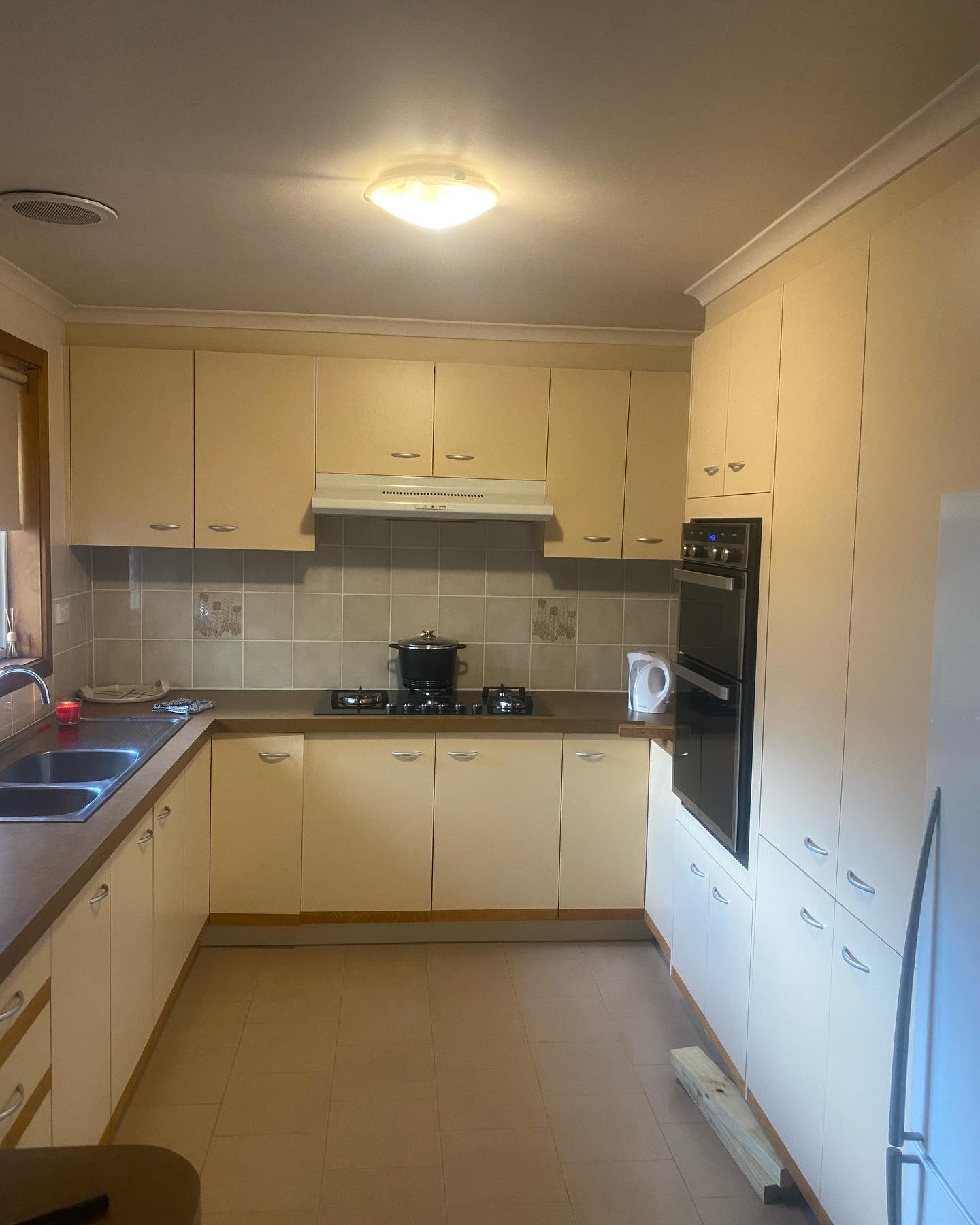 Kitchen before renovation with beige cabinets and drawers