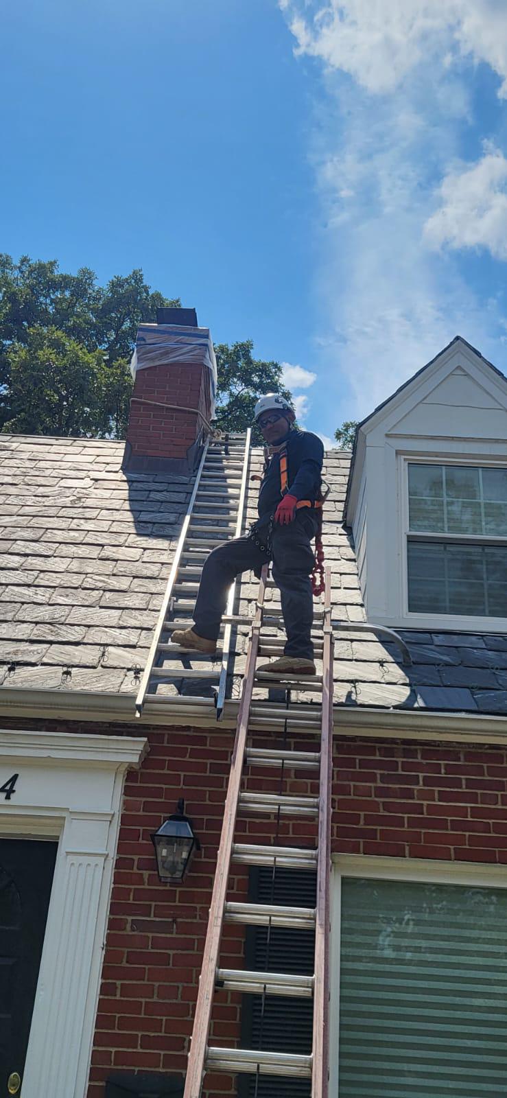 Technician standing on ladder placed against roof