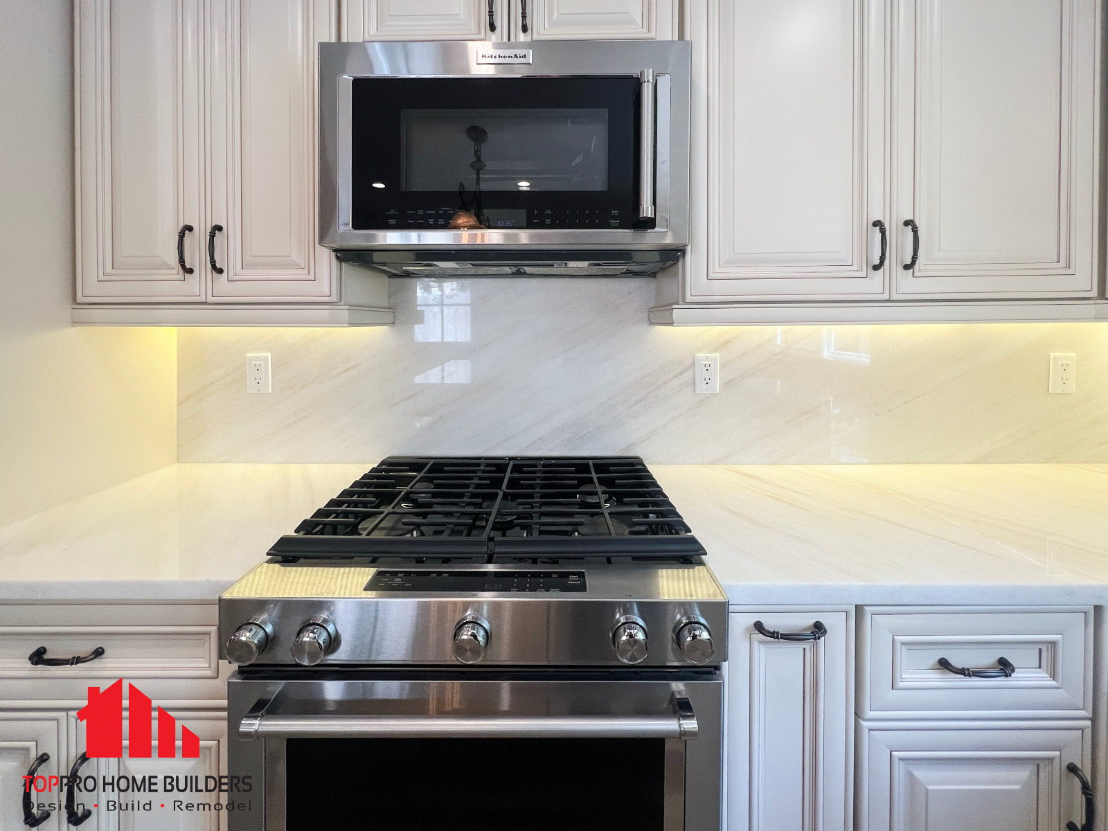 Stainless steel gas stove surrounded by white cabinetry