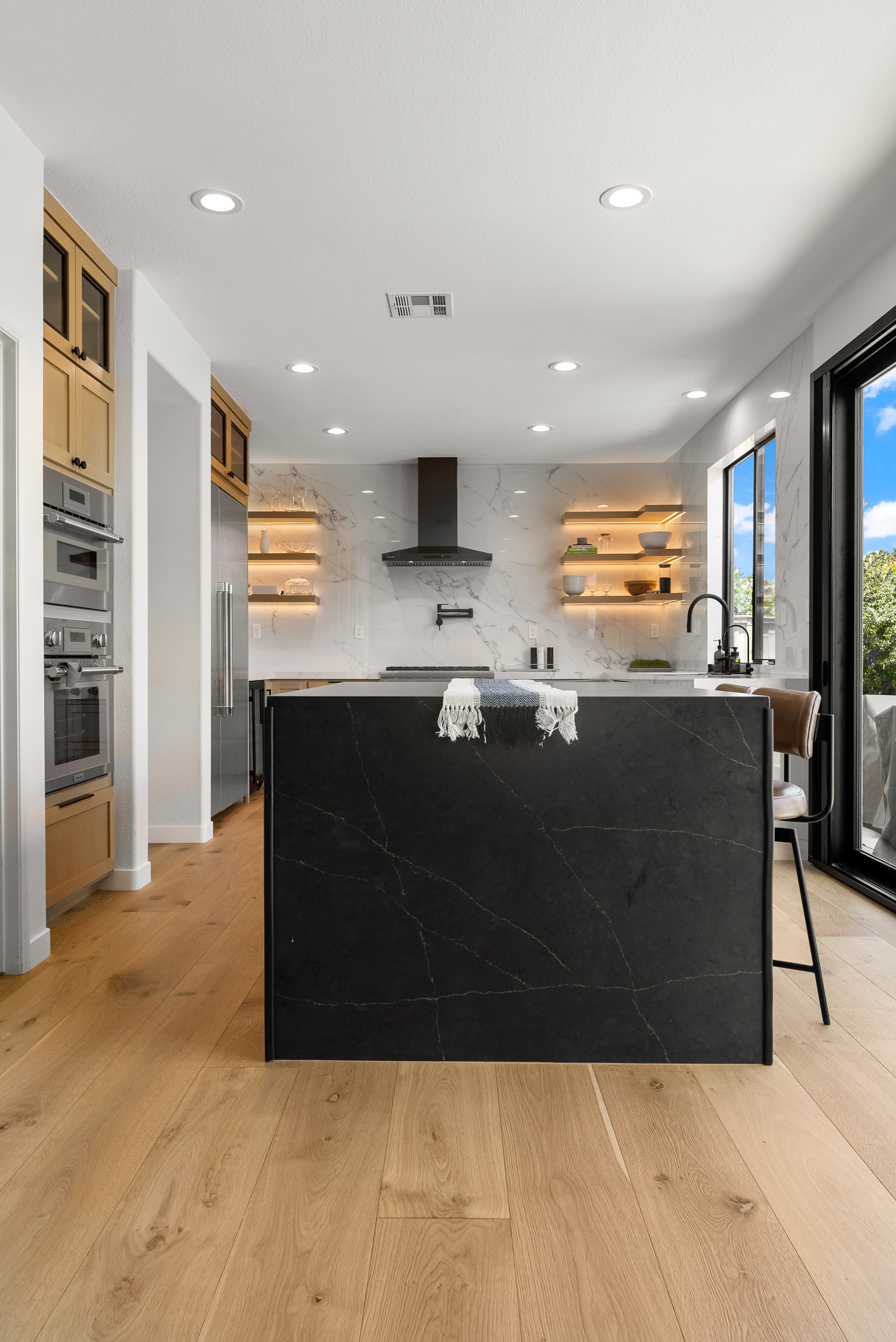 Modern kitchen featuring black marble island and wooden flooring