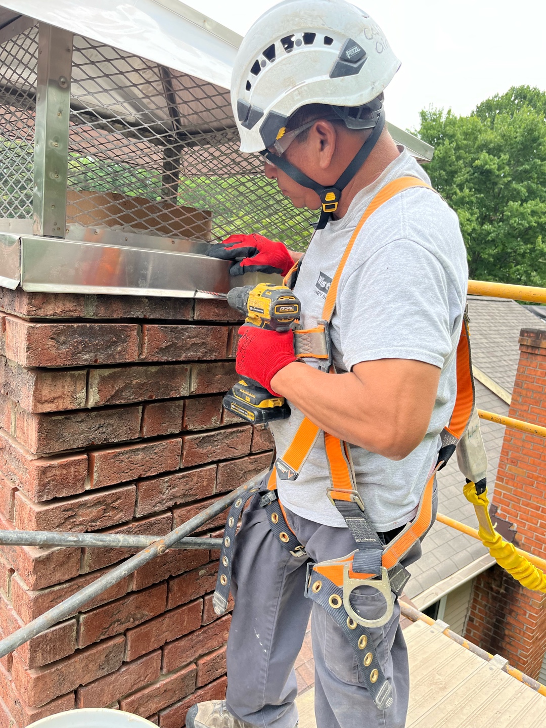 Worker using cordless drill on chimney