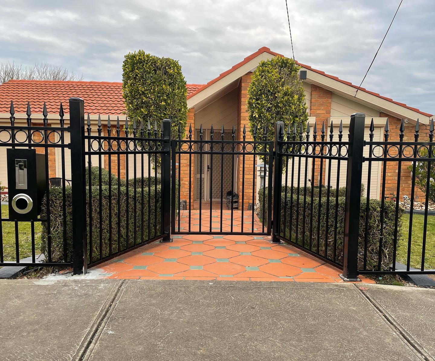 Black metal fence with built-in mailbox or intercom system