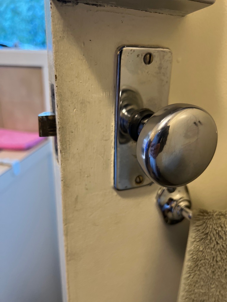 Reflective metallic door knob on white laundry door