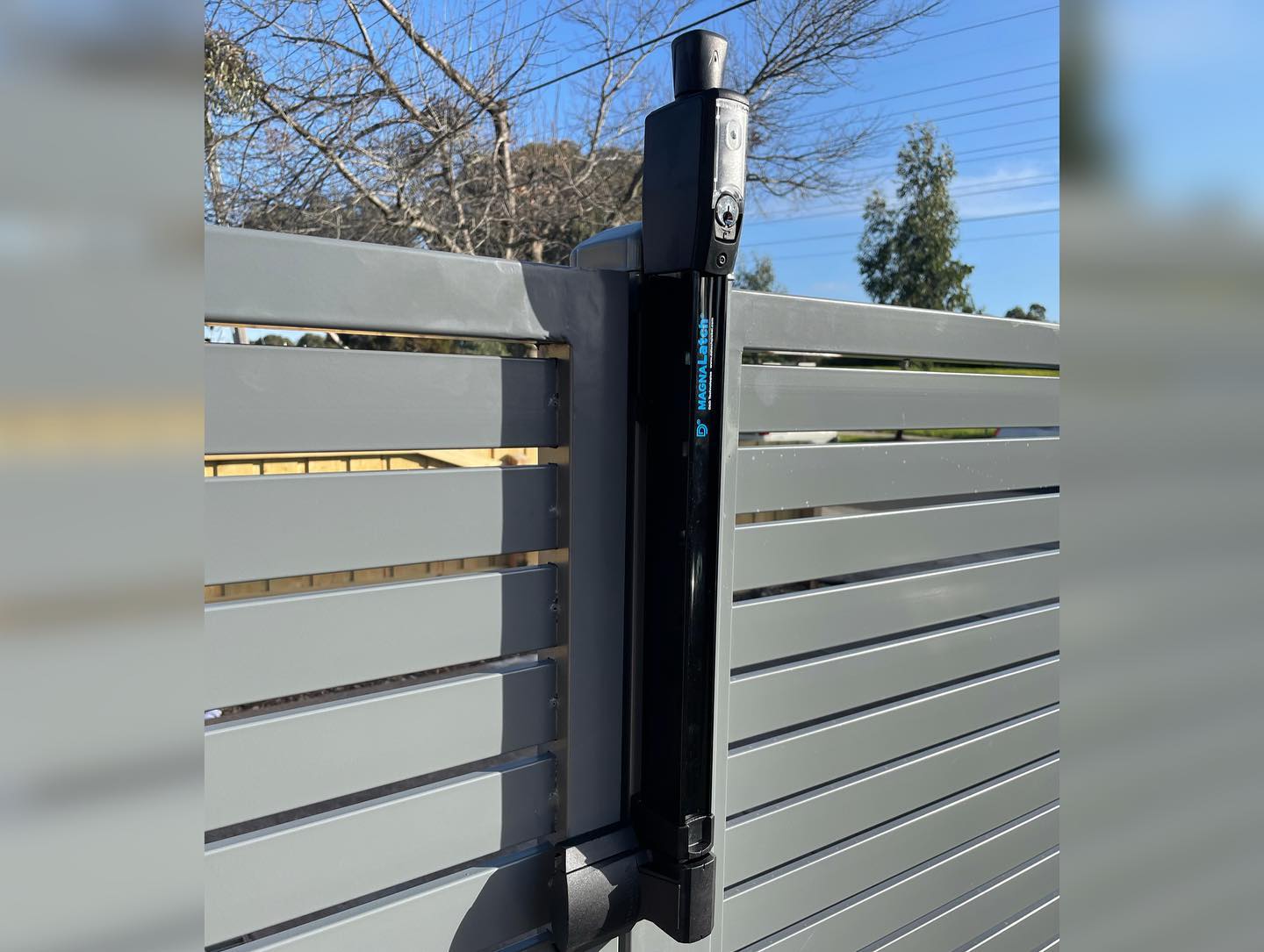Modern slat fence surrounding front yard of two-story brick house