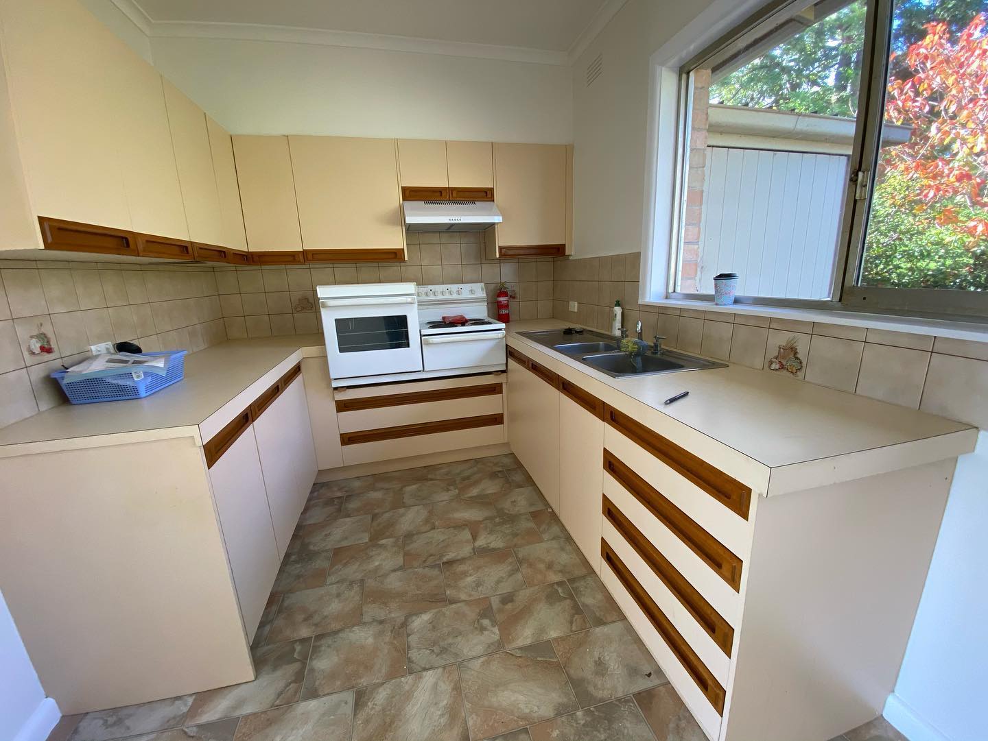 Beige kitchen cabinets with wooden handles after resurfacing