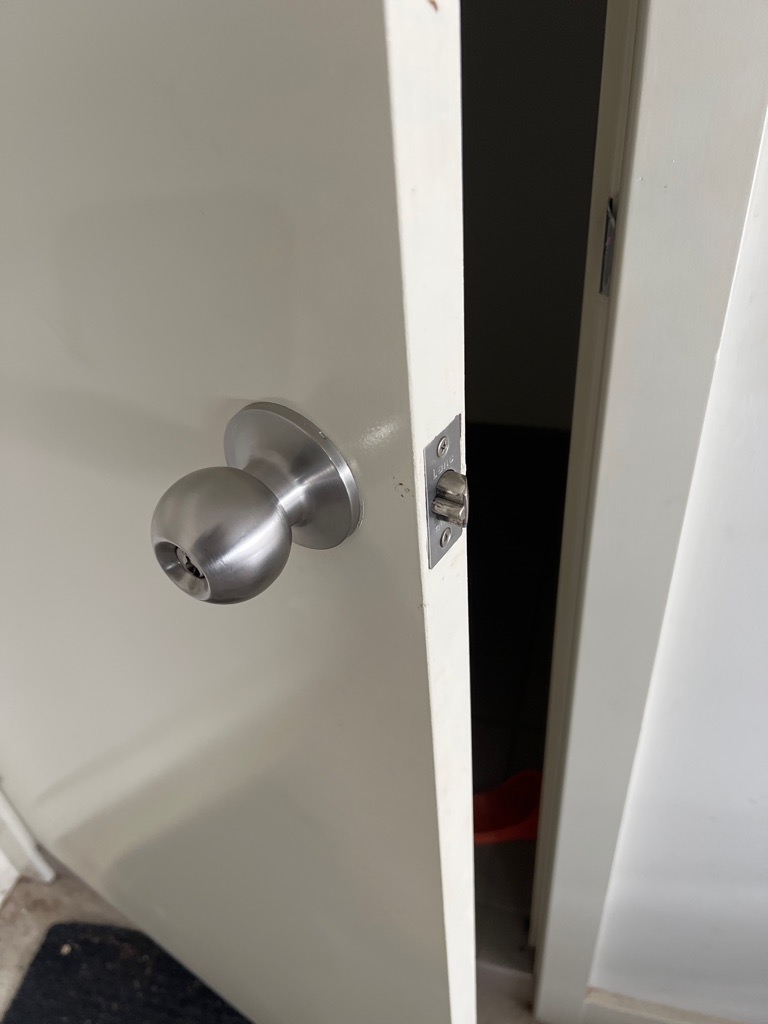 Partially open white door with silver doorknob