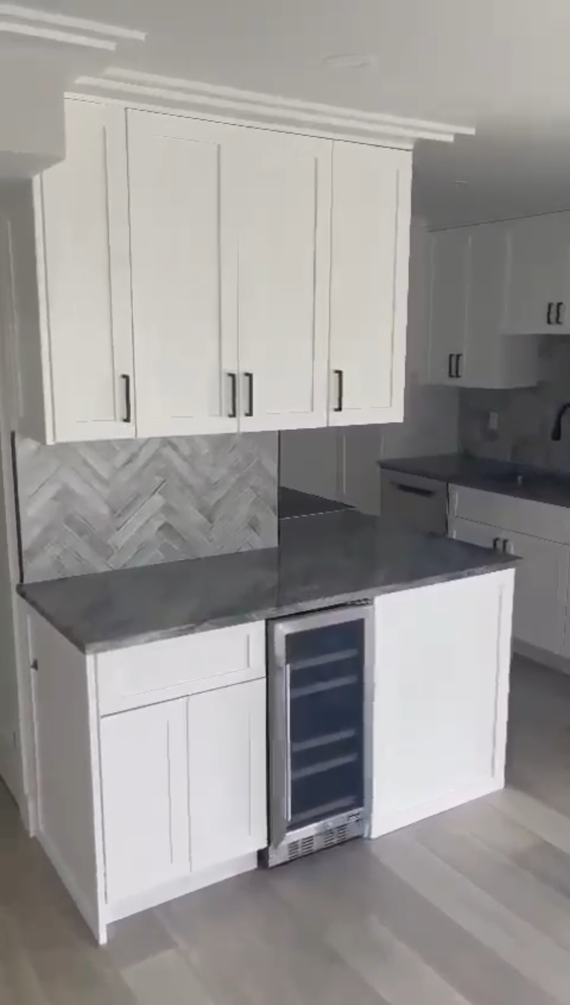 Modern kitchen setting with black handles and herringbone backsplash