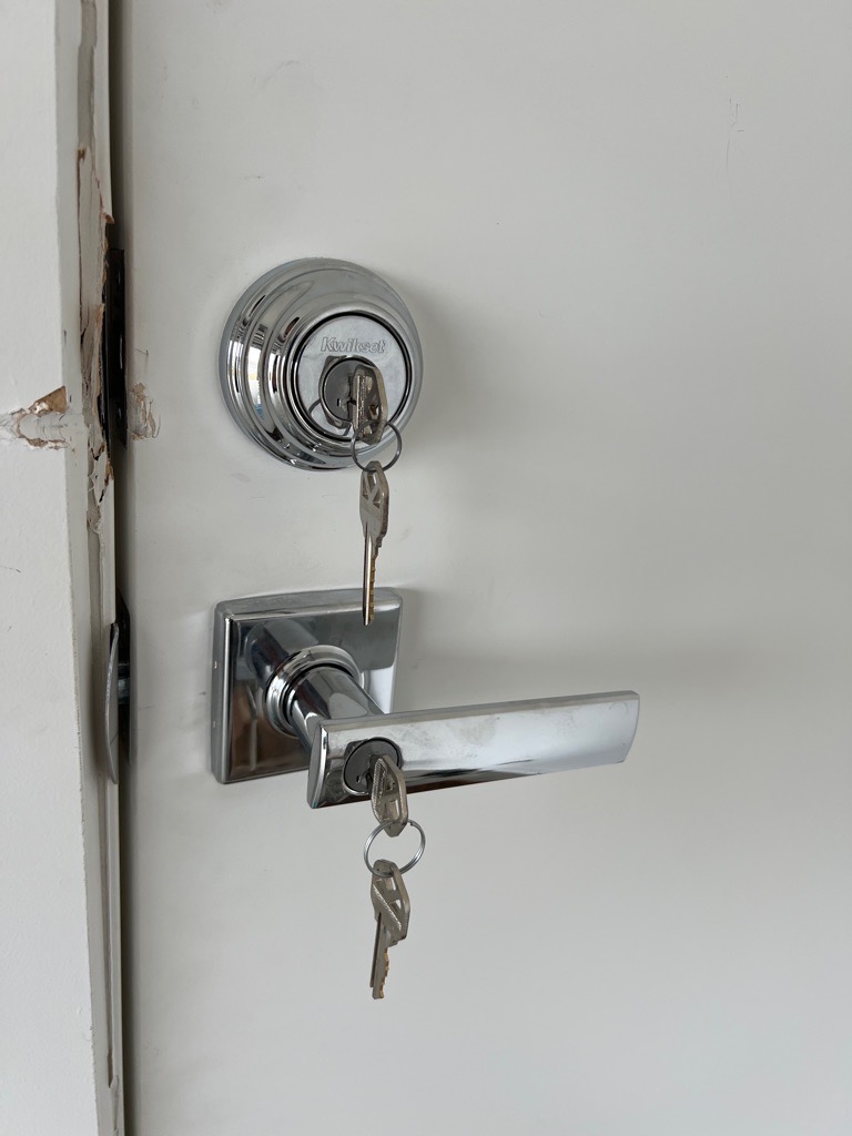 Newly installed deadbolt and entrance leverset on a white door