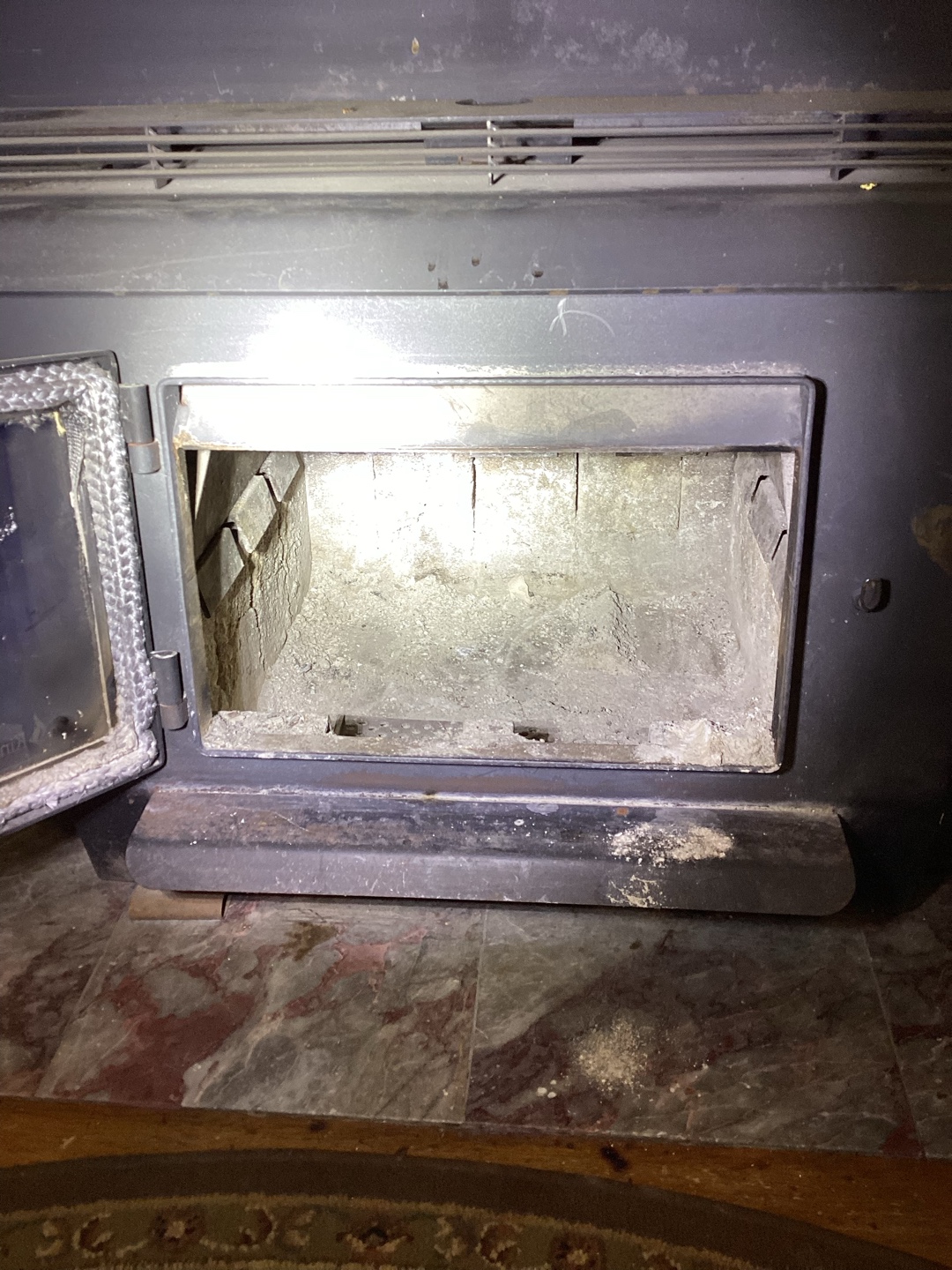 Open metal stove showing ash residue