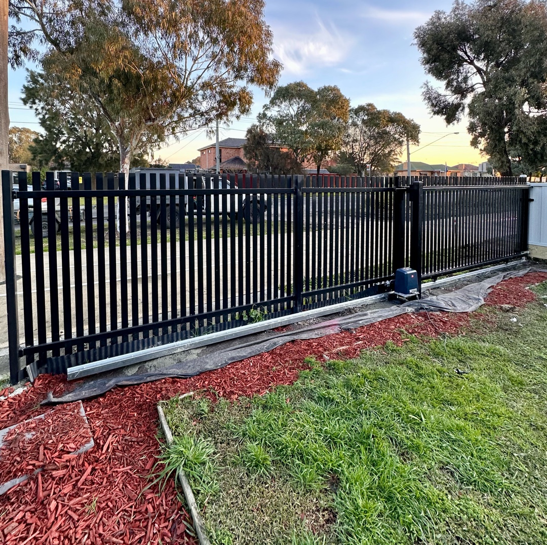 Black metal sliding gate along older existing fence